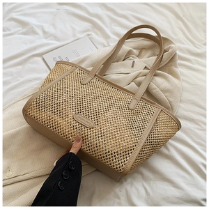 Détail d'un sac cabas en paille tressée avec bordures en cuir marron et logo de marque
