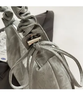 Close-up of a grey pleated handbag featuring silver metal hardware and bow drawstring detail