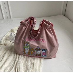 Detail der rosa Canvas-Tasche mit Hunde-Stickerei und rot-weiß geflochtenen Griffen