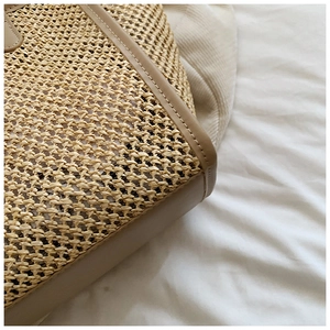 Gros plan sur la texture en paille tressée et bordure en cuir d'un grand sac cabas