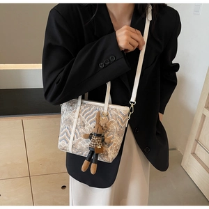 Detail of minimalist cream tote bag with blue patterns and cute plush rabbit charm