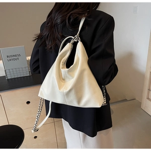 Close-up of quilted cream leather texture and chain strap on a vintage hobo bag