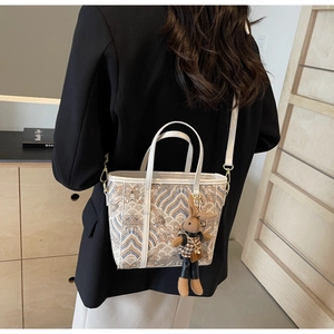 Detail of wave-patterned bucket bag featuring a cute plush bunny charm and golden hardware