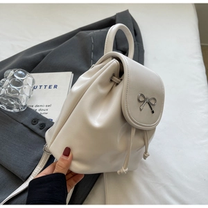 Detail of cream mini backpack with silver bow buckle on textured leather cover