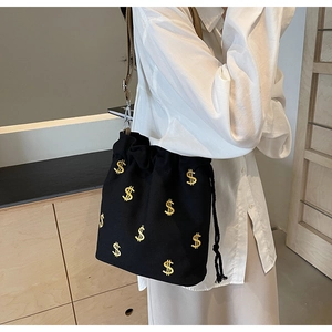 Détail du sac seau en toile noire avec broderie dollar doré et bandoulière marron