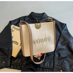 Close-up of cream and brown tote bag with FASHION embroidery and metal twist lock
