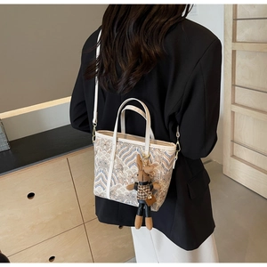 Detail of minimalist cream tote bag with wave embroidery and cute bunny charm pendant