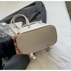 Detail of a creamy white mini PU leather backpack styled on a grey blazer