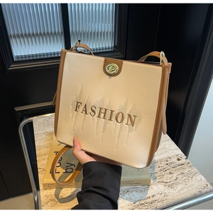 Close-up of beige and brown leather tote bag featuring fashion embroidery and gold lock