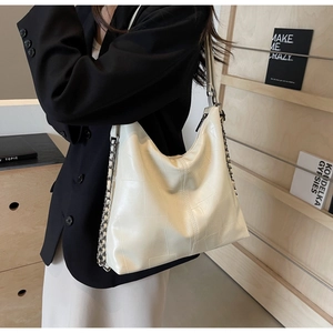 Detail shot of a large cream beige shoulder bag with vintage texture and chain accent
