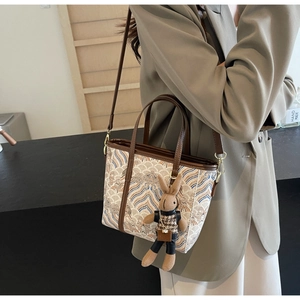 Detail of embroidered tote bag with wave patterns, leather handle and rabbit charm