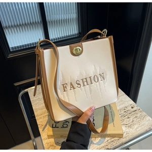 Detail of cream and brown tote bag featuring gold twist lock and Fashion embroidery