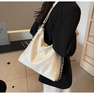 Detail of cream hobo bag featuring contrast stitching and silver chain leather strap