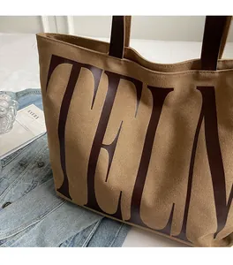 Gros plan du sac cabas en toile kaki montrant sa texture souple et son intérieur spacieux