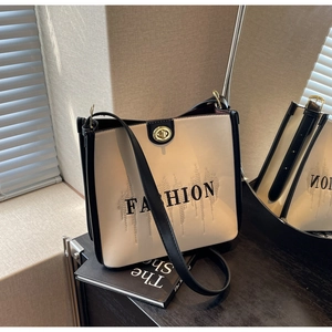 Detail of b&w tote bag featuring golden twist lock and FASHION letter print