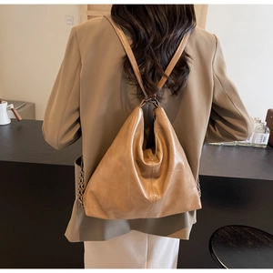 Detail of camel crocodile embossed backpack with slender straps and metal chain accents