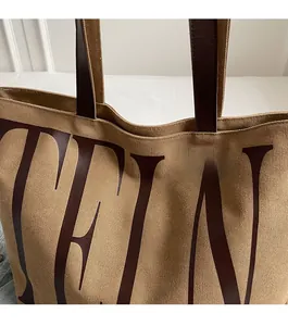 Détails des coutures de qualité sur les poignées en cuir brun du grand sac en toile