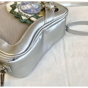 Détail du sac ita argenté montrant la fenêtre transparente avec badges et dentelle