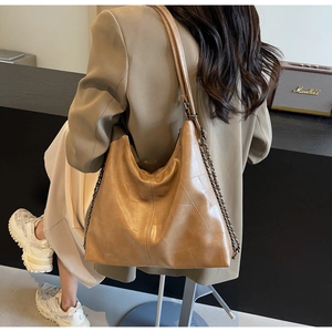 Brown vintage tote bag with patchwork texture and chain detail shown on model's shoulder