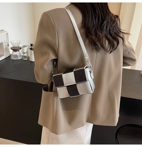 Detail of silver and black woven leather crossbody bag shown on model in a cafe setting