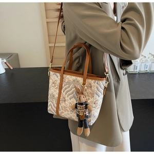 Detail of retro tote bag with wave patterns, leather handles, and a cute rabbit charm