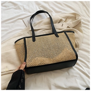 Détail d'un sac cabas en paille tressée avec bordure et poignées en cuir noir pour l'été