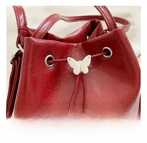 Dettaglio di una borsa tote bordeaux con elegante chiusura a farfalla in metallo argentato