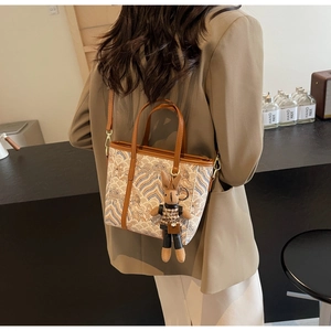 Detail of printed bucket bag with landscape pattern, brown leather trim, and rabbit charm