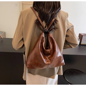 Detail of deep brown leather backpack with geometric stitching and soft triangle silhouette