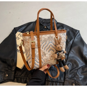 Detail of jacquard bucket bag with rabbit charm and leather trim on leather jacket