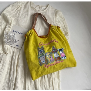 Detail der gelben Stoff-Tote Bag mit bunten Hunde-Stickereien und geflochtenen Seilgriffen