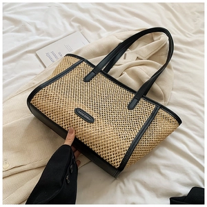Détail du sac cabas en paille avec bordure en cuir noir et logo HOCOMU sur lit blanc