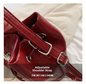 Dettaglio di spallacci regolabili con fibbie argentate su borsa tote in pelle cerata rossa