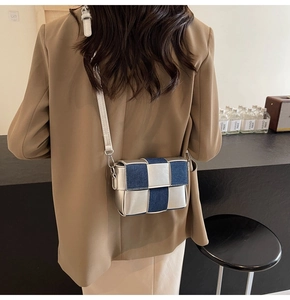 Detail of blue denim and silver woven crossbody bag shown on a khaki blazer