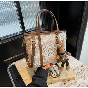 Detail of vintage jacquard bucket bag with brown leather trim and cute rabbit charm