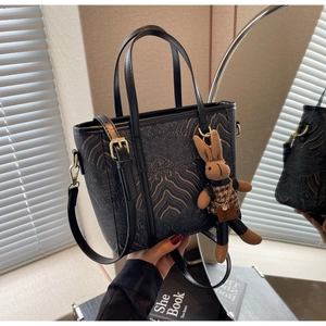 Detail of vintage bronze embossed pattern on black leather bucket bag with bunny charm