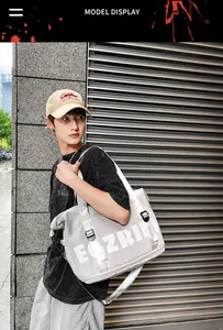 Detail of grey Oxford tote bag with silver webbing straps and white letter logo
