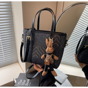 Detail of vintage black bucket bag with totem prints, golden hardware and rabbit charm