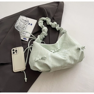 Close-up of light green pleated shoulder bag with marble print and bow detail