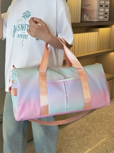 Large gradient travel bag with shoulder strap shown held by model in a cozy interior