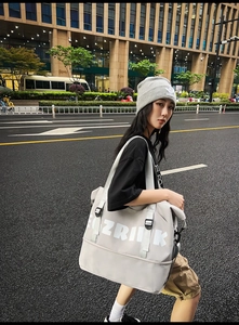 Close-up of grey Oxford cloth tote bag showing white letter print and adjustable buckles