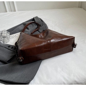 Detail of dark brown vintage tote bag with quilted stitching and chain shoulder strap