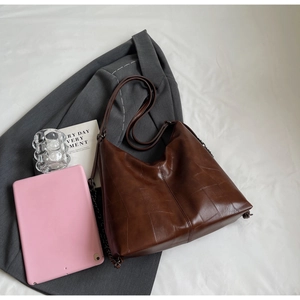 Detail view of dark brown leather tote bag with geometric stitching and metal chain