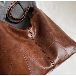 Close-up of caramel brown tote bag featuring geometric patchwork and premium leather texture