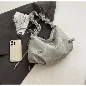 Detail showing marble texture faux leather and bow accents on a pleated hobo bag