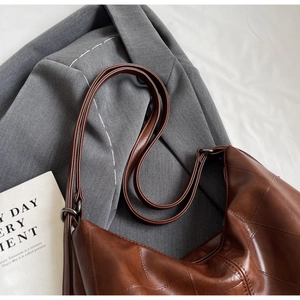 Detailed view of brown textured leather shoulder bag with vintage metal hardware