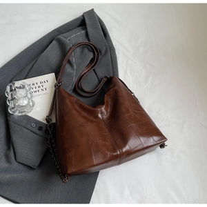 Close-up of vintage dark brown leather tote bag with geometric stitching and metal chain