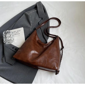 Detail of vintage brown tote bag featuring geometric stitching and dark metal chain