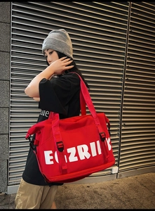 Detail of red oxford travel bag showing durable fabric and artistic white logo lettering