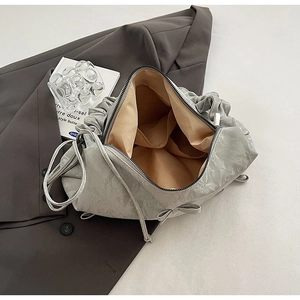 Detail view of the pleated shoulder bag with interior pockets and bow tie decoration